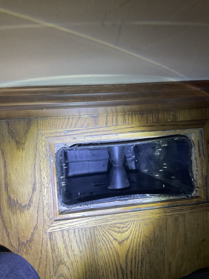 Wood-framed duct access with dark metal ductwork visible