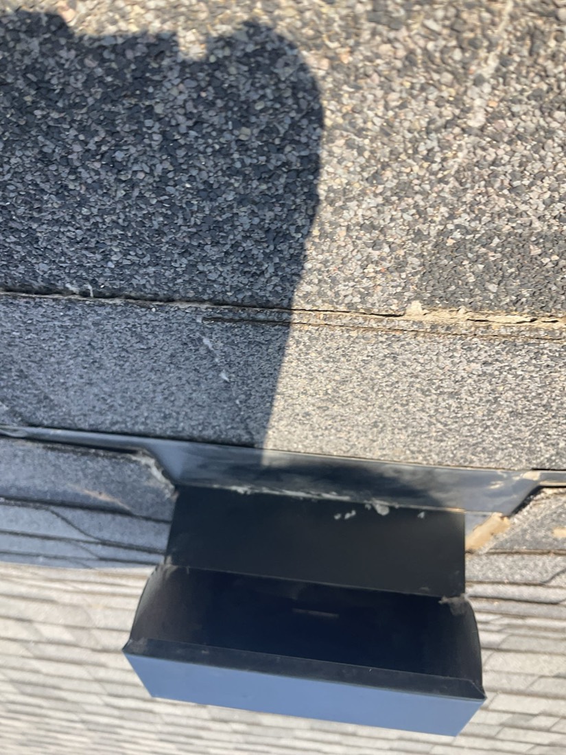Black dryer vent hood with metal flashing on roof shingles