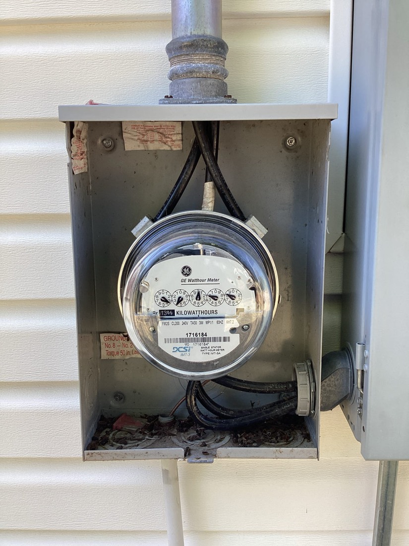 GE watthour meter installed in weatherproof enclosure on exterior wall.