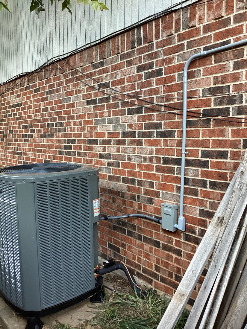 Installed outdoor AC unit with refrigerant lines and electrical conduit