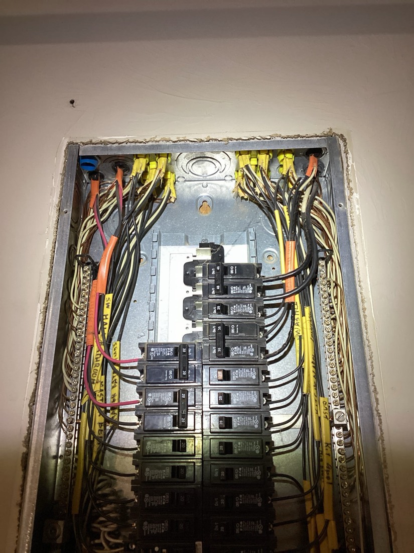 Upgraded electrical panel with circuit breakers and organized yellow and black wiring
