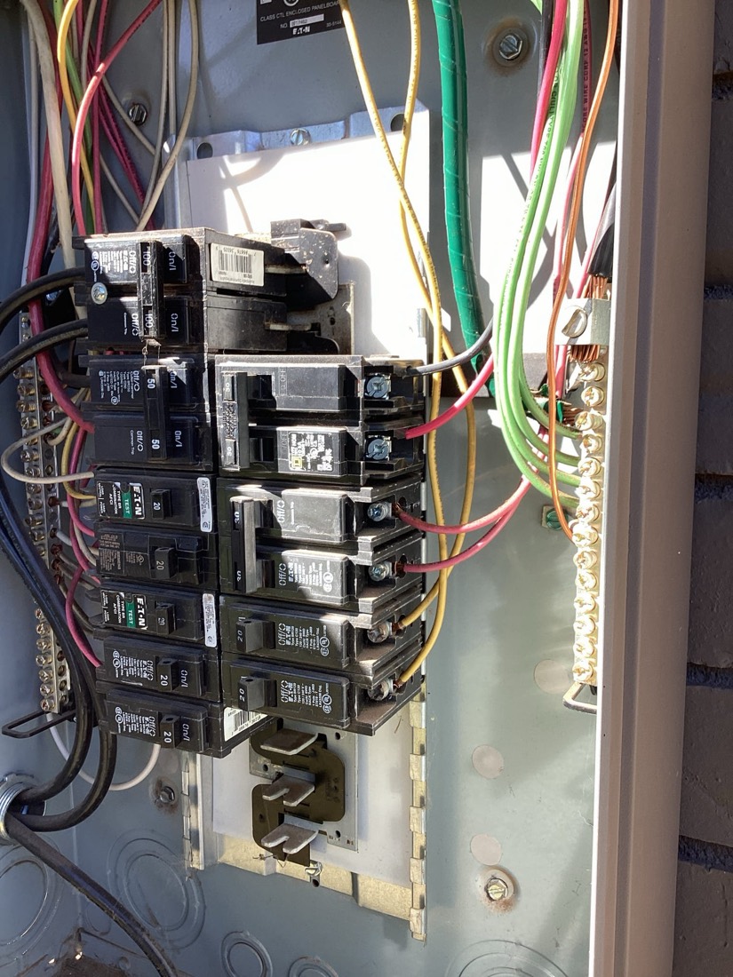 Electrical breaker panel with multiple black breakers and color-coded wires neatly arranged