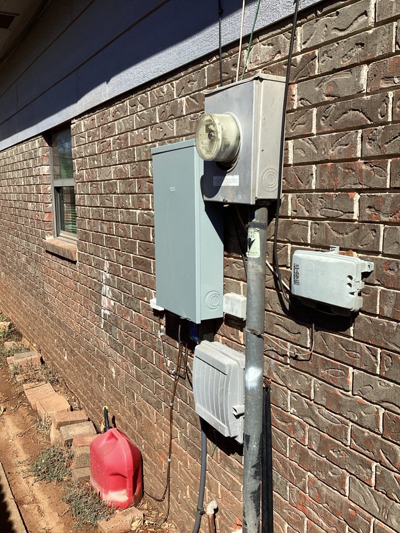 Electrical meter mounted on brick house exterior.