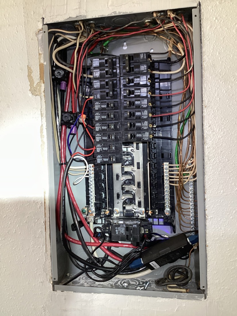 Finished electrical panel with organized circuit breakers and color-coded wires