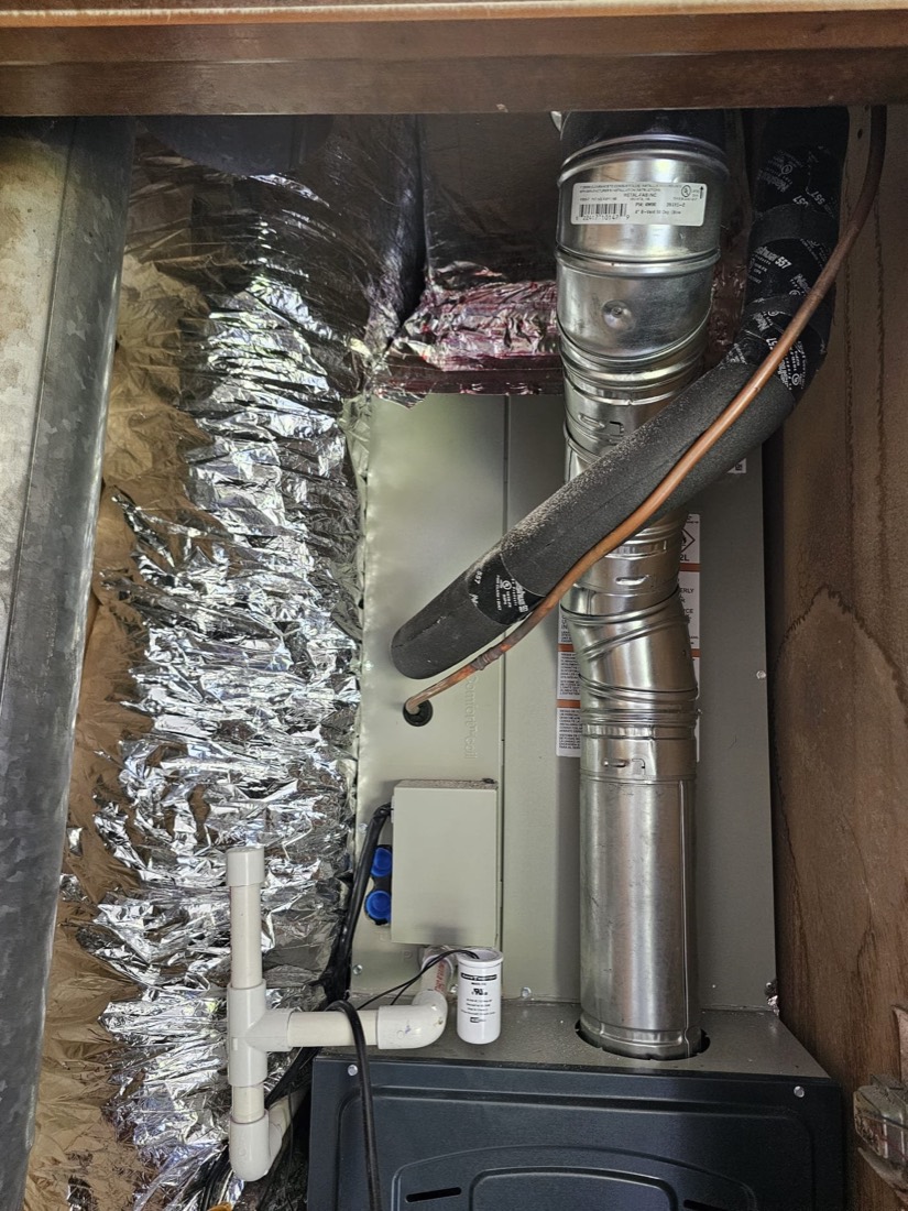 Installed AC evaporator coil with copper refrigerant tubing and insulation