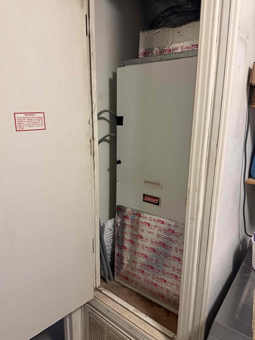 Heat pump unit with piping and insulation in utility closet.